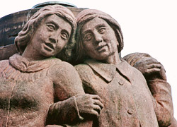 Aus Rotsandstein gemeißelte sich an Händen haltende Figuren am Brunnen in Bornheim Mitte, Frankfurt am Main.